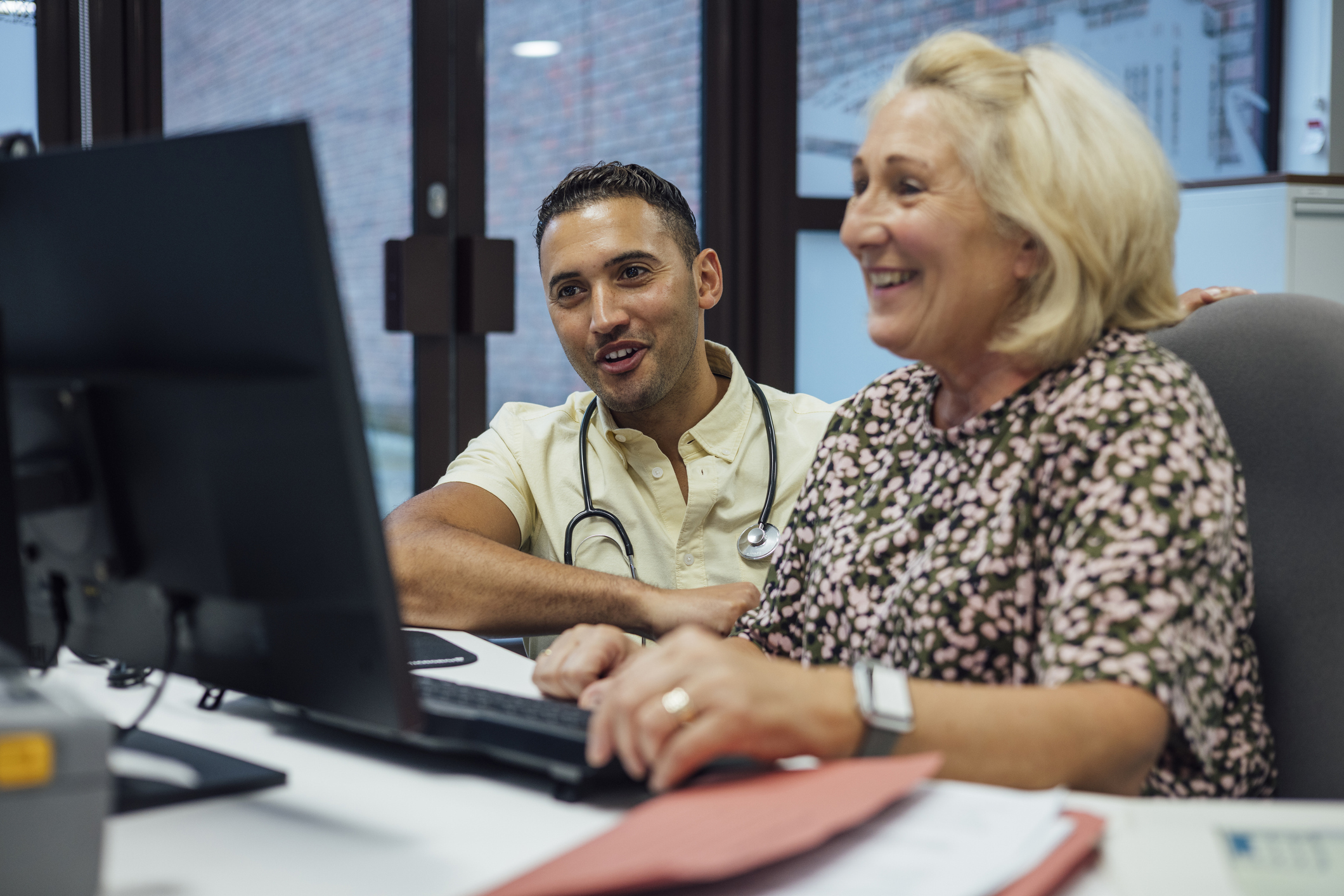A medium close cup of a GP and his medical secretary going over some patient records and checking the patient lists for the day. They are in the reception area of the surgery in Newcastle Upon Tyne int the North East of England.