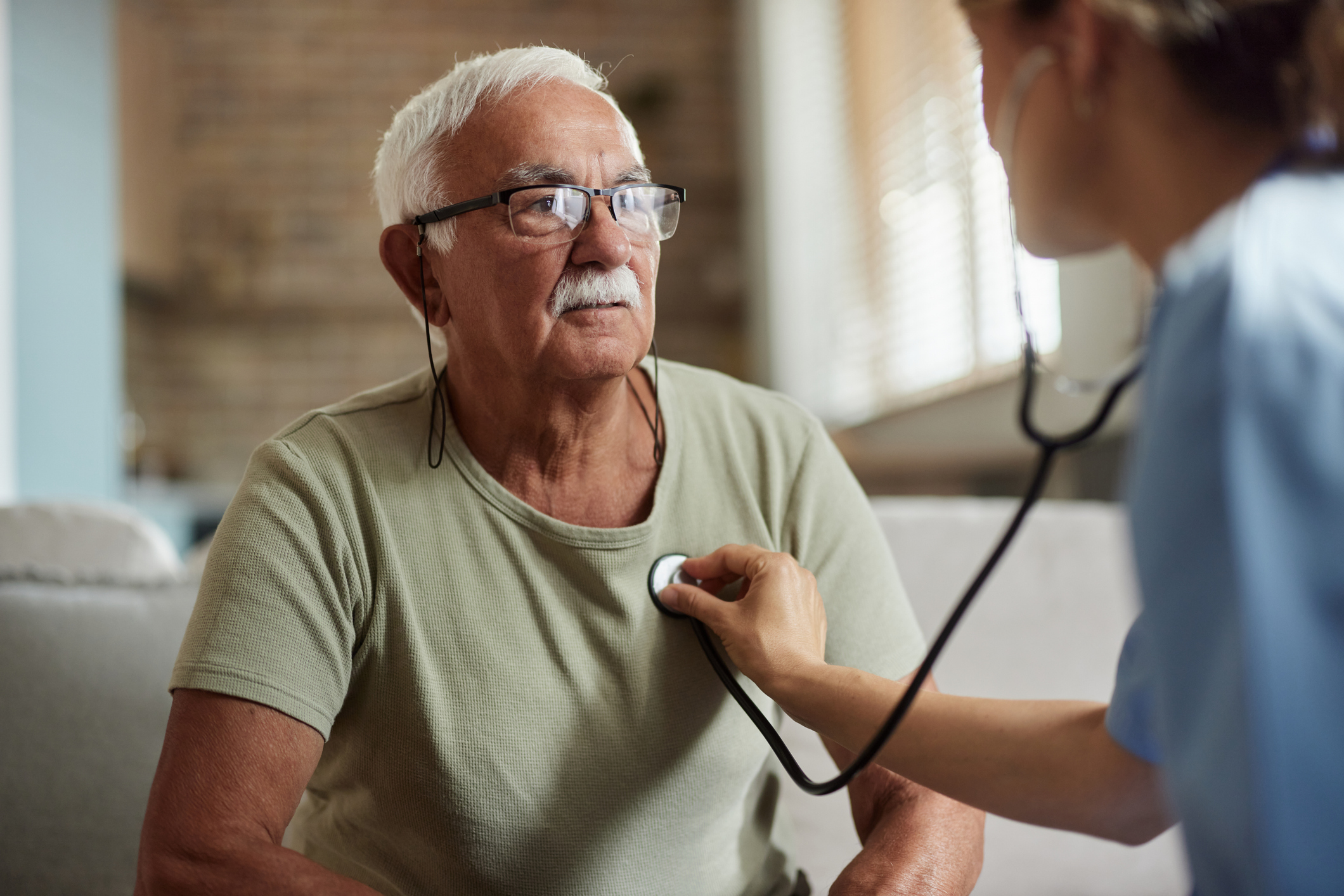 Female doctor listening to senior man's heartbeat with a stethoscope.